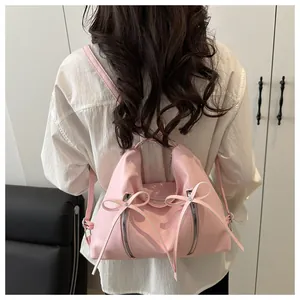 Detail of sweet pink backpack with bow design and metal zippers on a model's back