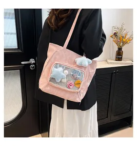 Pink Ita bag with transparent window showing plush charms and badges on a model