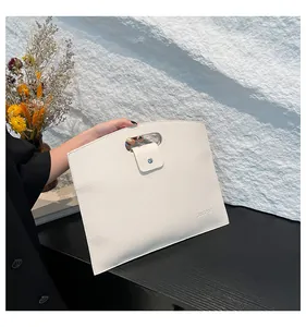 Détail du sac d'ordinateur blanc motif litchi avec poignée découpée et fermoir métallique