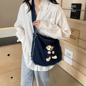 Denim tote bag with frayed edges and cute plush bear accessory in front pocket