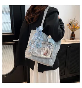 Detail of light blue ita bag featuring transparent window lace trim and bear charm accessory