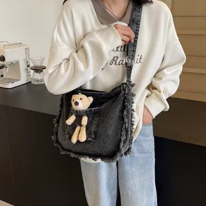 Large black denim tote bag with plush bear charm and stylish frayed fringe edges