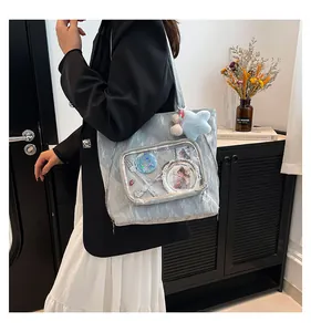Detail of light blue ita bag with transparent front pocket showing anime badges and star charm