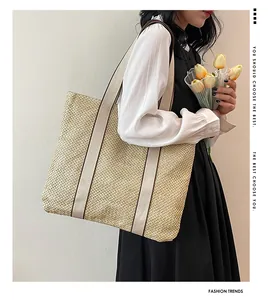 Detail of minimalist straw tote bag featuring wide canvas straps and rich woven texture