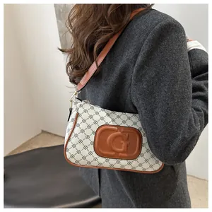 Detail of white monogram shoulder bag with brown leather trim worn by model in grey coat