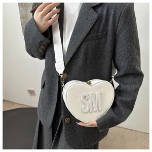 Detail of white heart-shaped crossbody bag with bold SM letter and wide strap