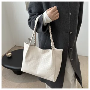 Detail of soft cream tote bag featuring textured pattern and braided handles