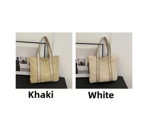 Detail of woven straw tote bags in khaki and white showing texture and shoulder straps
