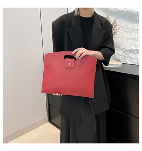 Détail du sac cabas en cuir rouge montrant la texture grainée et le bouton pression