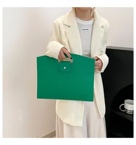 Détail du sac cabas vert en cuir grainé avec poignée découpée et fermeture à pression