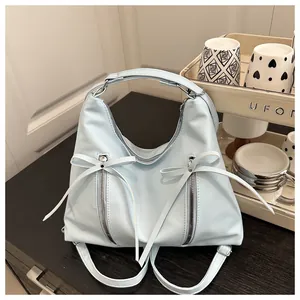 Close-up of light blue PU bag with silver zippers and elegant bow ribbon decorations