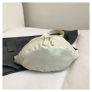 Detail view of cream crescent crossbody bag with dual zippers and woven strap on gray blazer