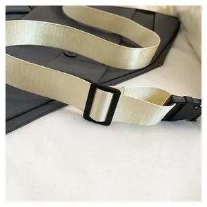 Detail of adjustable off-white nylon strap with black quick-release plastic buckles