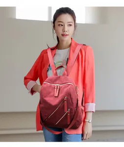 Detail of burgundy corduroy backpack with dual diagonal silver zippers on casual outfit