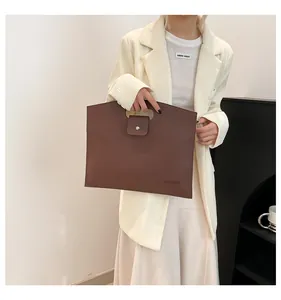 Détail du sac cabas en cuir marron foncé montrant la poignée et la texture grainée
