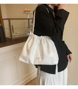 Detail of white pleated cloud bag with silver bow accent on a shoulder tote