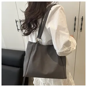 Detail of dark grey textured canvas tote bag with wide strap on white lace dress
