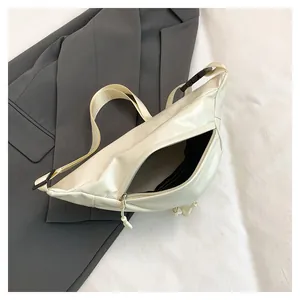 Detail of cream white PU leather crossbody bag with adjustable strap on grey suit fabric