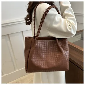 Detail of deep brown houndstooth pattern and braided strap on soft leather tote bag