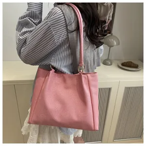 Detail shot of a pink woven tote bag with gold metal rings and slim shoulder straps