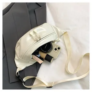 Detail view of cream white glossy waist bag with double zippers and adjustable strap