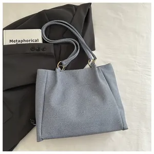 Top view of light blue textured tote bag with golden metal rings on white fabric