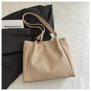 Detail of light brown woven tote bag featuring dual straps and gold metal ring hardware