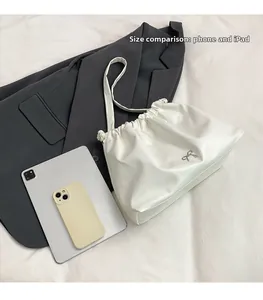 Size comparison of the white pleated tote bag next to an iPad and a smartphone