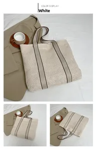 Detail of white woven tote bag with contrast edge handles and textured straw pattern