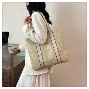Detail of woven straw tote bag with cream ribbon handles in a minimalist office setting