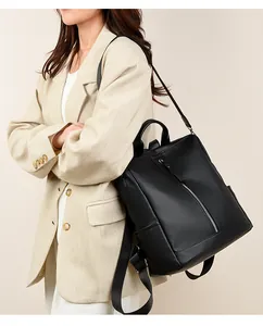 Detail of black pebbled leather backpack showing silver zippers and versatile shoulder straps