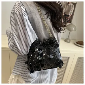 Detailed view of shimmering black sequins and elegant gold chain strap on the handbag