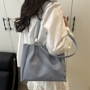 Minimalist grey-blue canvas tote bag with wide shoulder strap and gold ring details