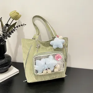 Light green nylon ita bag tote with clear window and plush star accessory in a lifestyle setting