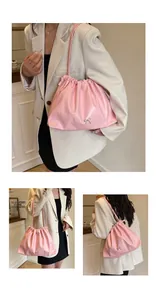 Detailed view of pink drawstring bucket bag with metallic bow and pleated leather texture