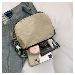 Detail of beige corduroy pillow bag showing spacious interior with striped shoulder strap