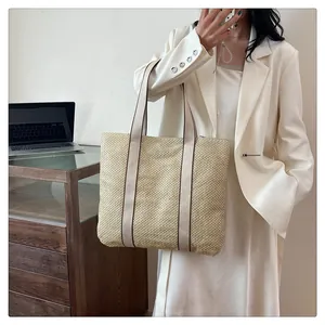 Detail of minimalist straw tote bag featuring contrast handles in a casual setting