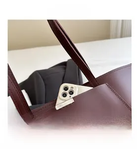 Détail de la poche avant du fourre-tout marron foncé avec un smartphone pour la taille