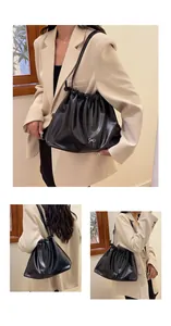 Detail of black pleated cloud bag with silver bow accent and adjustable shoulder strap