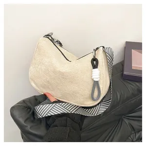 Detail view of beige corduroy hobo bag with trendy black and white striped woven strap