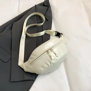 Top view of cream white leather sling bag with dual zippers and nylon strap on grey blazer