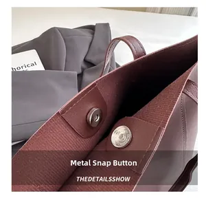 Gros plan du fermoir magnétique argenté sur le sac cabas en cuir bordeaux grainé