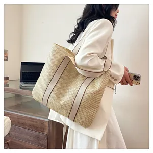 Detailed view of beige straw tote bag with canvas straps worn by a model in office