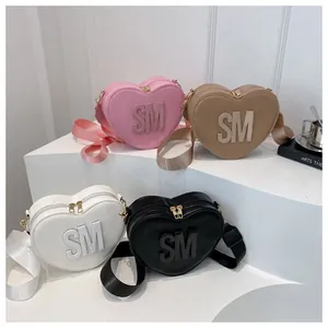 Detail view of heart-shaped crossbody bags in pink, khaki, white, and black colors