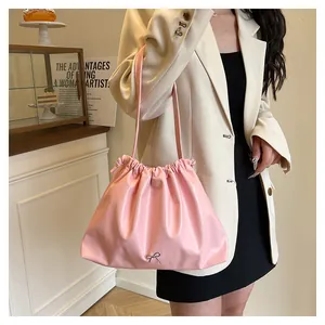 Detail of pink pleated tote bag with silver bow buckle worn on shoulder