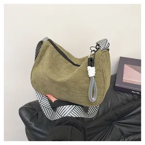 Detail of dark green corduroy bag showing ribbed texture and geometric woven strap