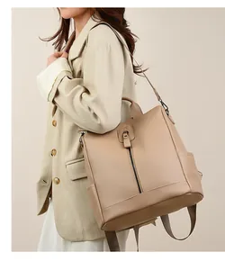 Detail of apricot pebbled leather backpack shown as a shoulder bag on a model