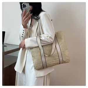 Detail of hand-woven straw tote bag texture and reinforced canvas shoulder straps