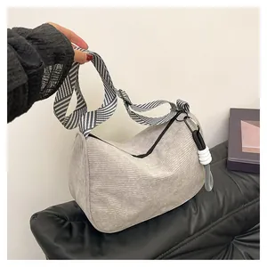Detail of light gray corduroy bag with textured fabric and wide striped shoulder strap