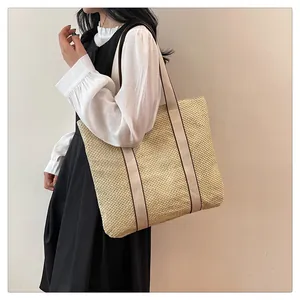 Detail of a beige woven tote bag with wide cream shoulder straps on a casual model